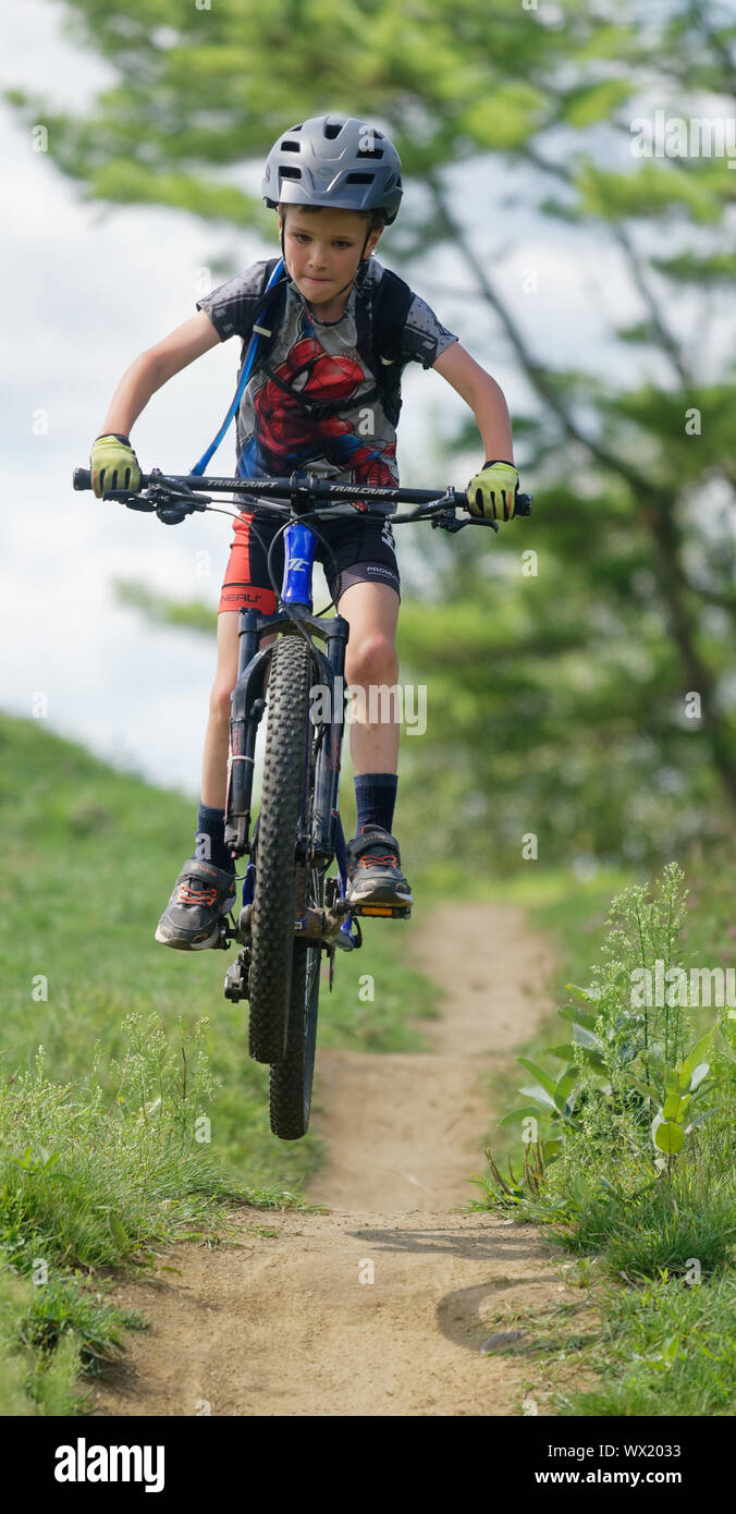 Un niño de siete años haciendo salta sobre su bicicleta de montaña Foto de stock