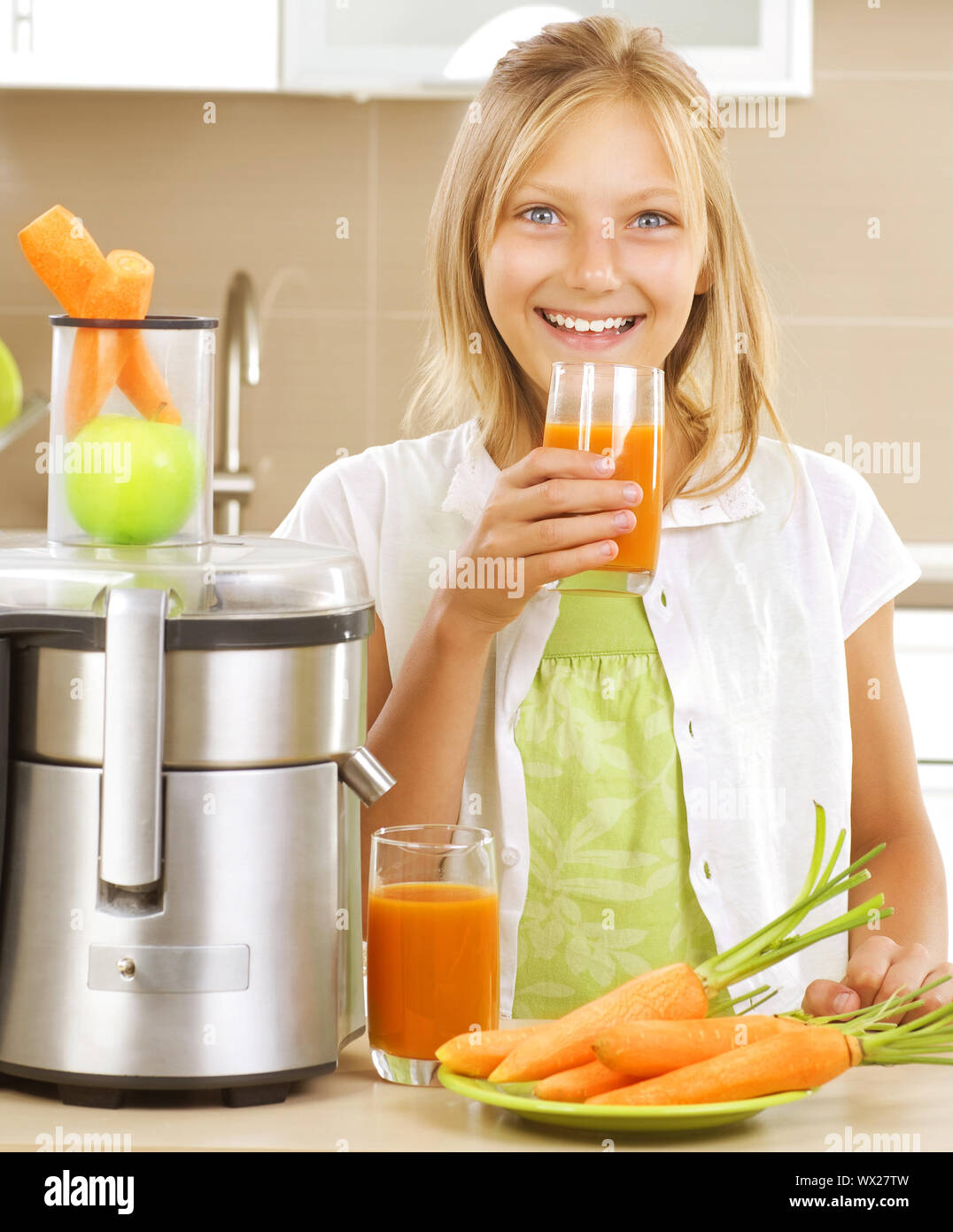 Niña alegre de beber jugo de manzana y zanahoria fresca. Extractor de jugos  saludables en su estilo de vida Fotografía de stock - Alamy