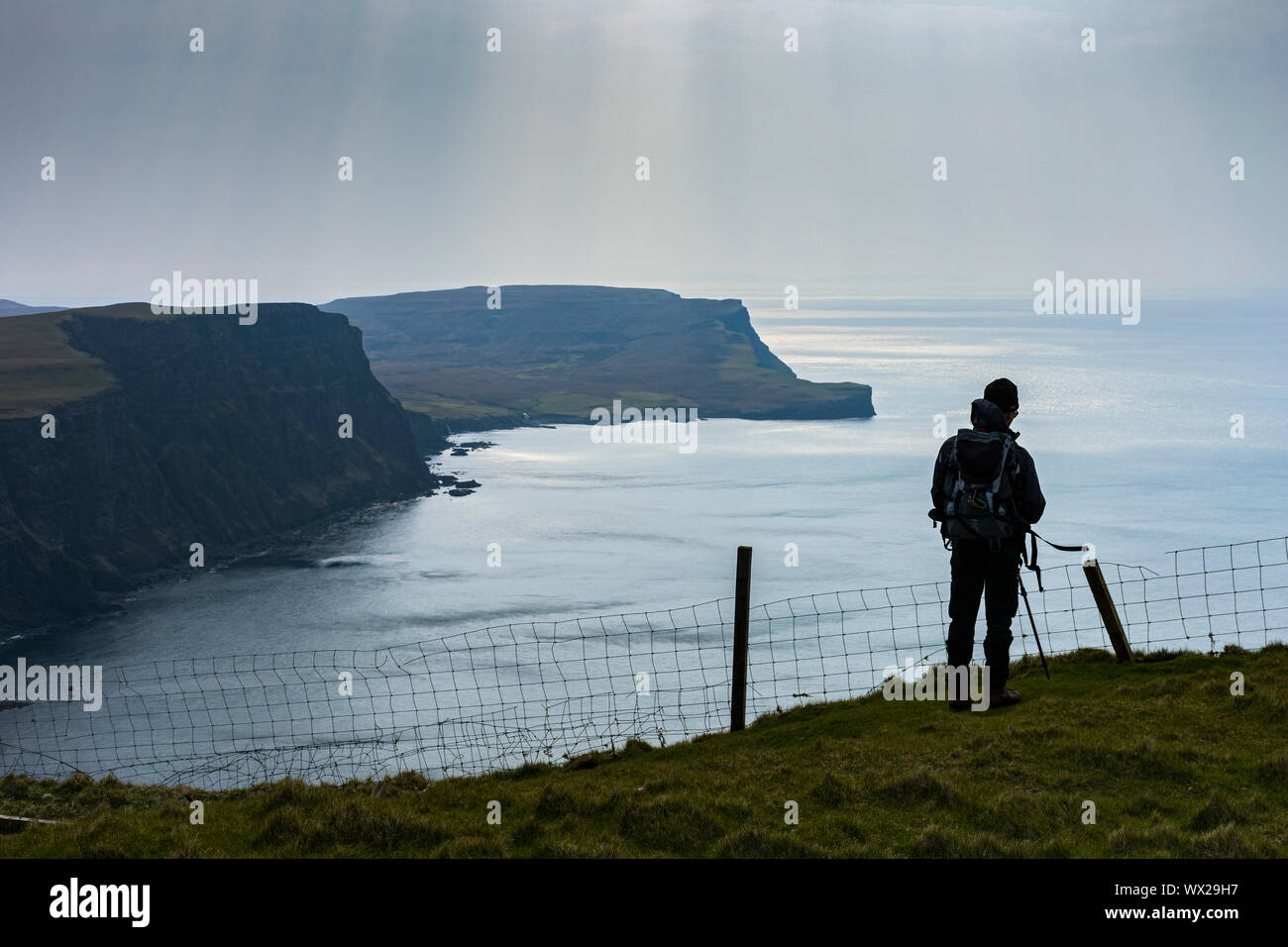 Un andador en Waterstein cabeza mirando al sur sobre Moonen Bay a Ramasaig Cliff y la azada, Duirinish, Isla de Skye, Escocia, Reino Unido Foto de stock