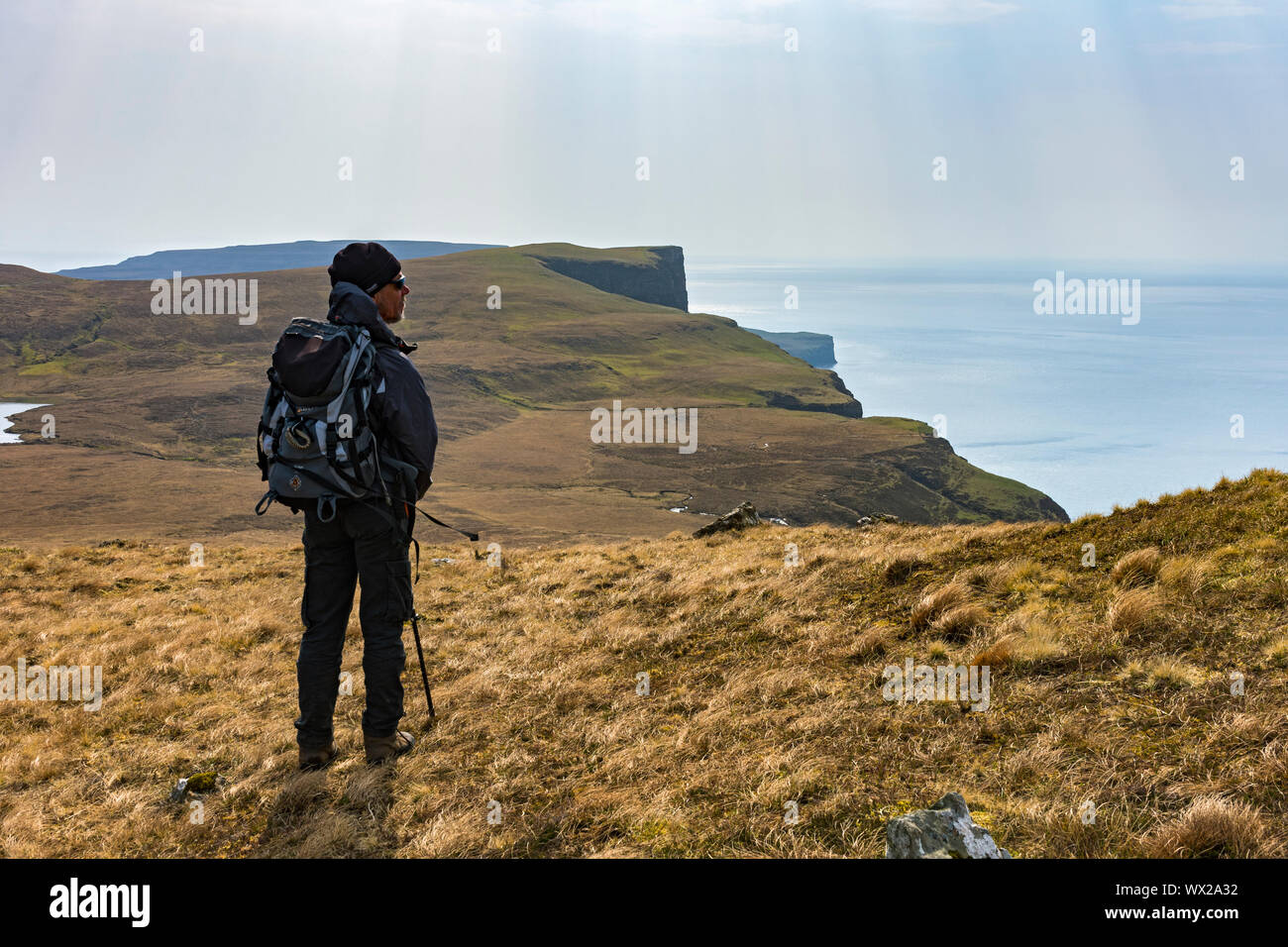 Un andador en las laderas orientales de Waterstein cabeza mirando al sur a Ramasaig Cliff y la azada, Duirinish, Isla de Skye, Escocia, Reino Unido Foto de stock
