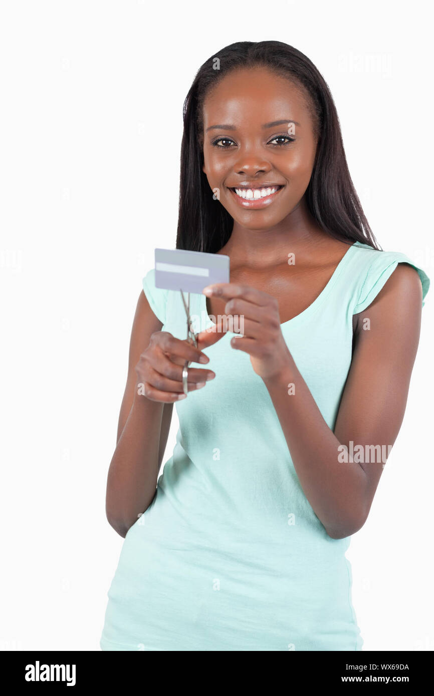 Feliz mujer sonriente destruyendo su tarjeta de crédito contra un fondo blanco. Foto de stock