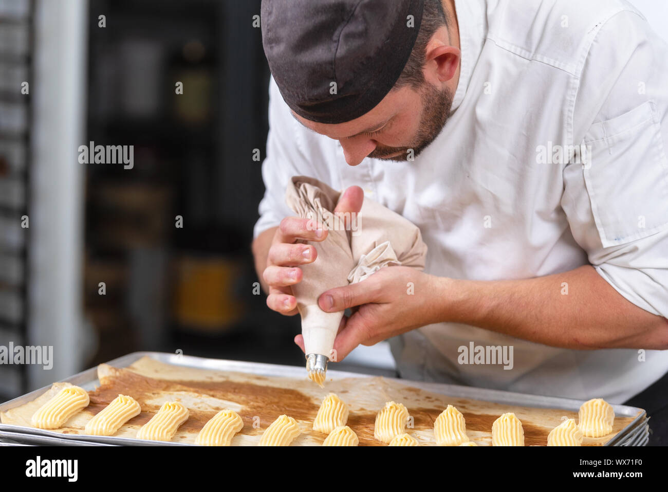 Chef de repostería con dulces bolsa exprimiendo crema en pastelería. Foto de stock