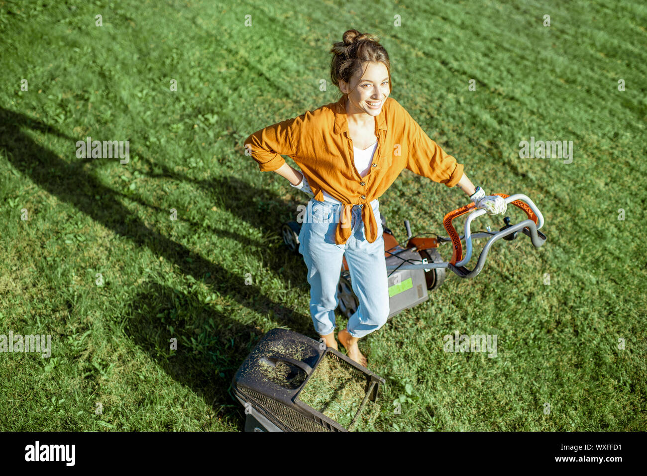 Mujer joven que corta el césped con un cortacésped manual del empuje  Fotografía de stock - Alamy