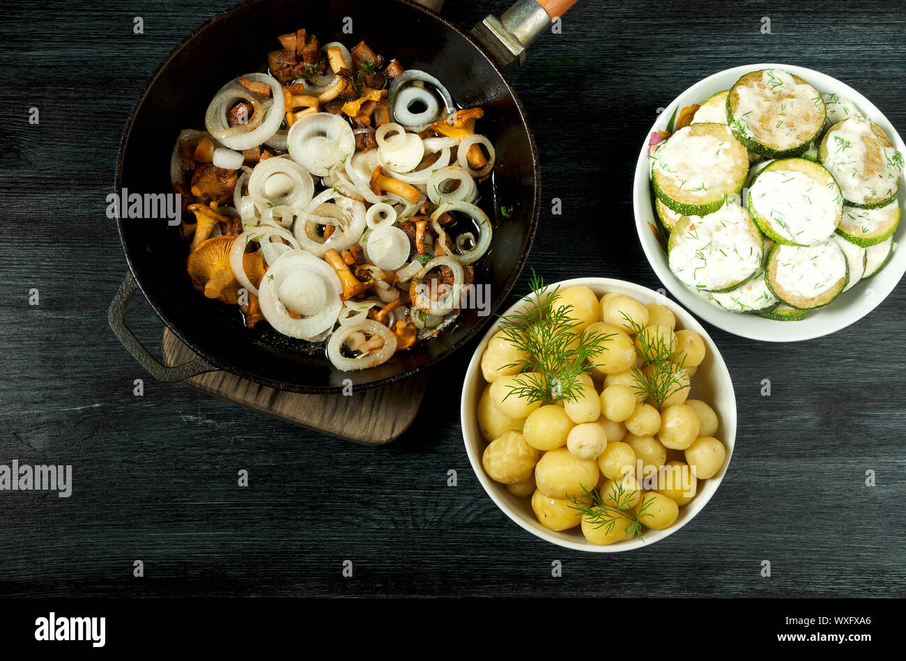 Las verduras en el fondo. Salsa de calabacín fritas en un plato. Los jóvenes patatas cocidas con eneldo en un recipiente. Fried cantharellus mush Foto de stock