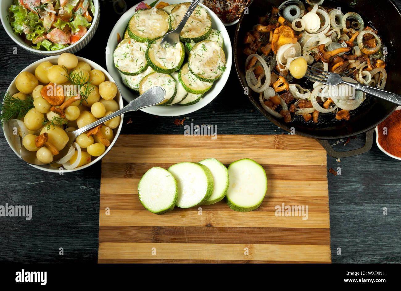 Las verduras en el fondo. Salsa de calabacín fritas en un plato. Los jóvenes patatas cocidas con eneldo en un recipiente. Fried cantharellus mush Foto de stock