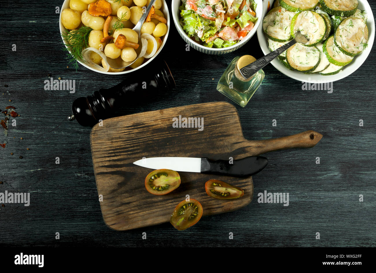 Las verduras en el fondo. Salsa de calabacín fritas en un plato. Los jóvenes patatas cocidas con eneldo en un recipiente. Fried cantharellus mush Foto de stock