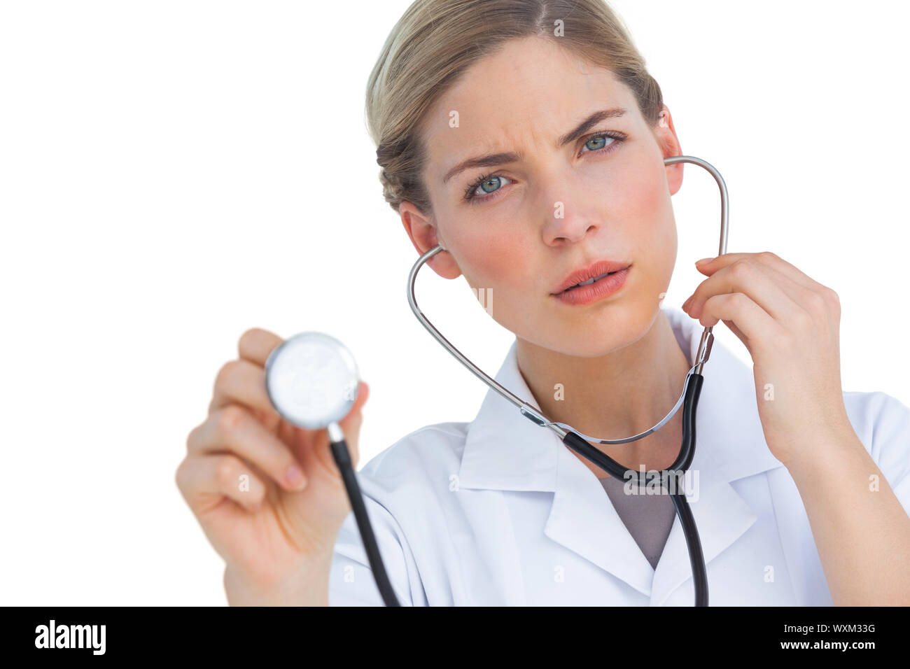 Preocupado enfermera escucha el estetoscopio sobre fondo blanco. Foto de stock