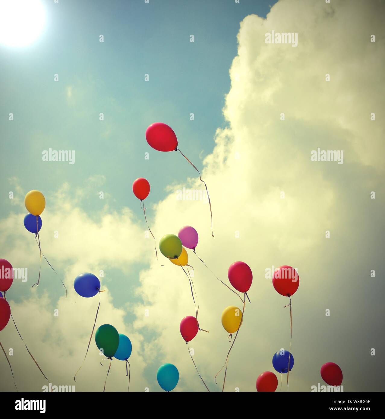 Muchos globos de colores vuelan a la luz en el cielo azul con nubes grande  durante una celebración con efecto tonos antiguos Fotografía de stock -  Alamy