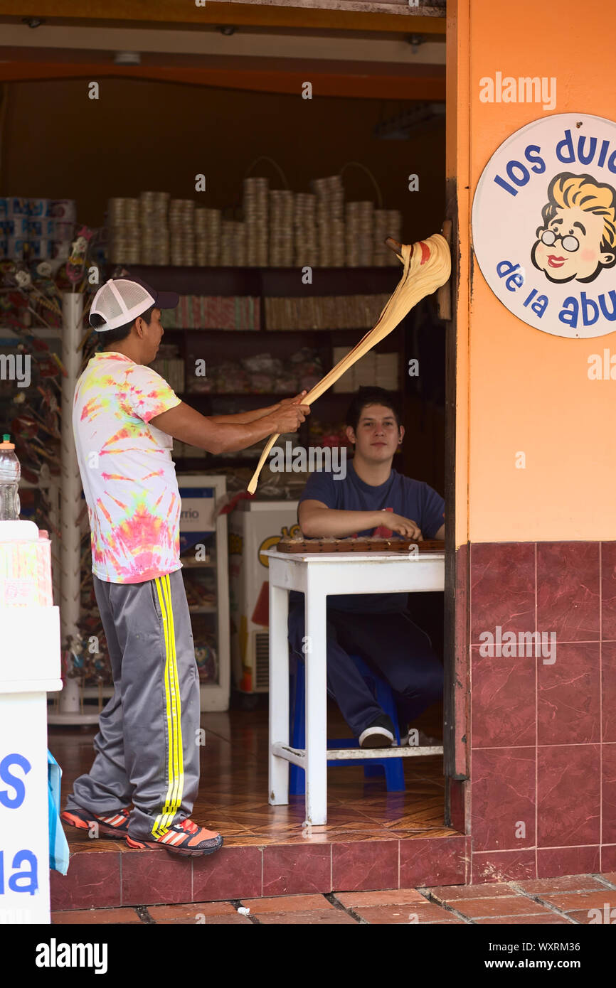 BANOS, ECUADOR - 25 DE FEBRERO de 2014: Jóvenes no identificados que preparan el tradicional tafy artesanal llamado Melcocha hecho de azúcar de caña Foto de stock