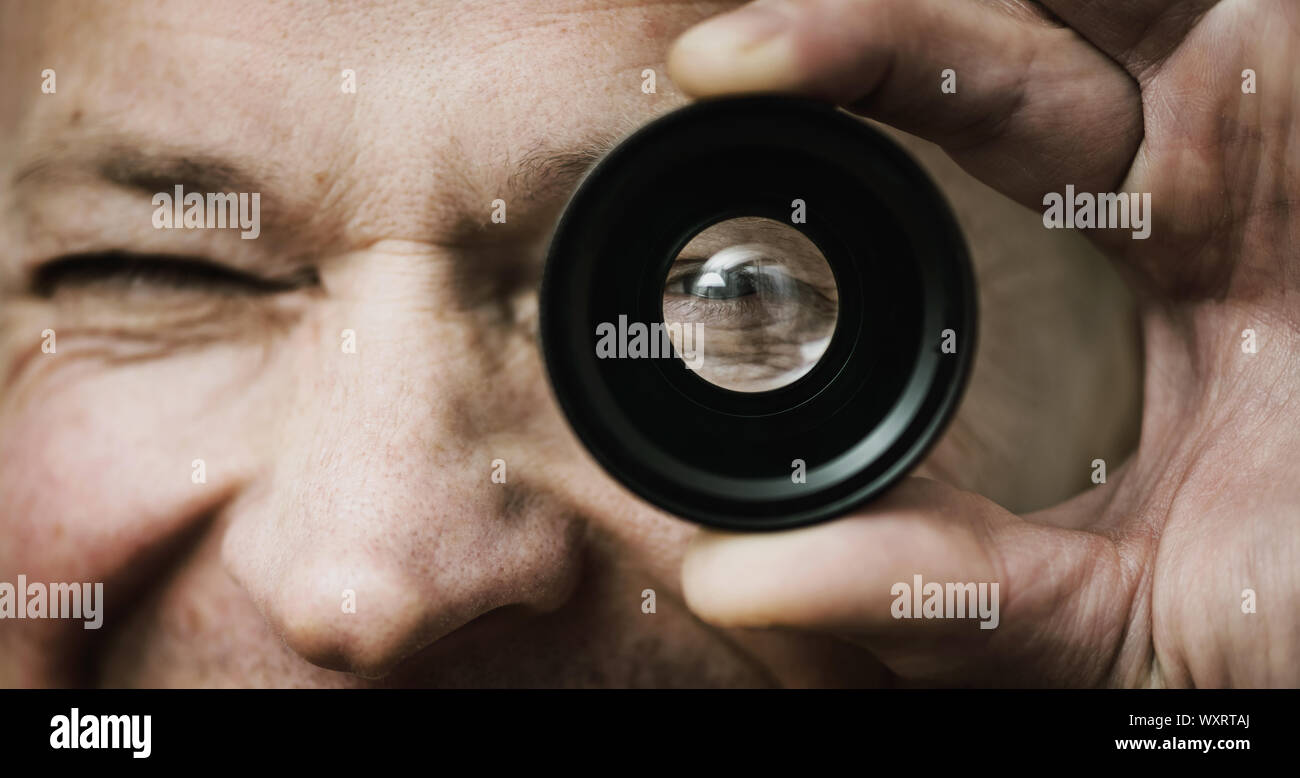El hombre se mantiene y mirando a través del lente fotográfico. Foto de stock