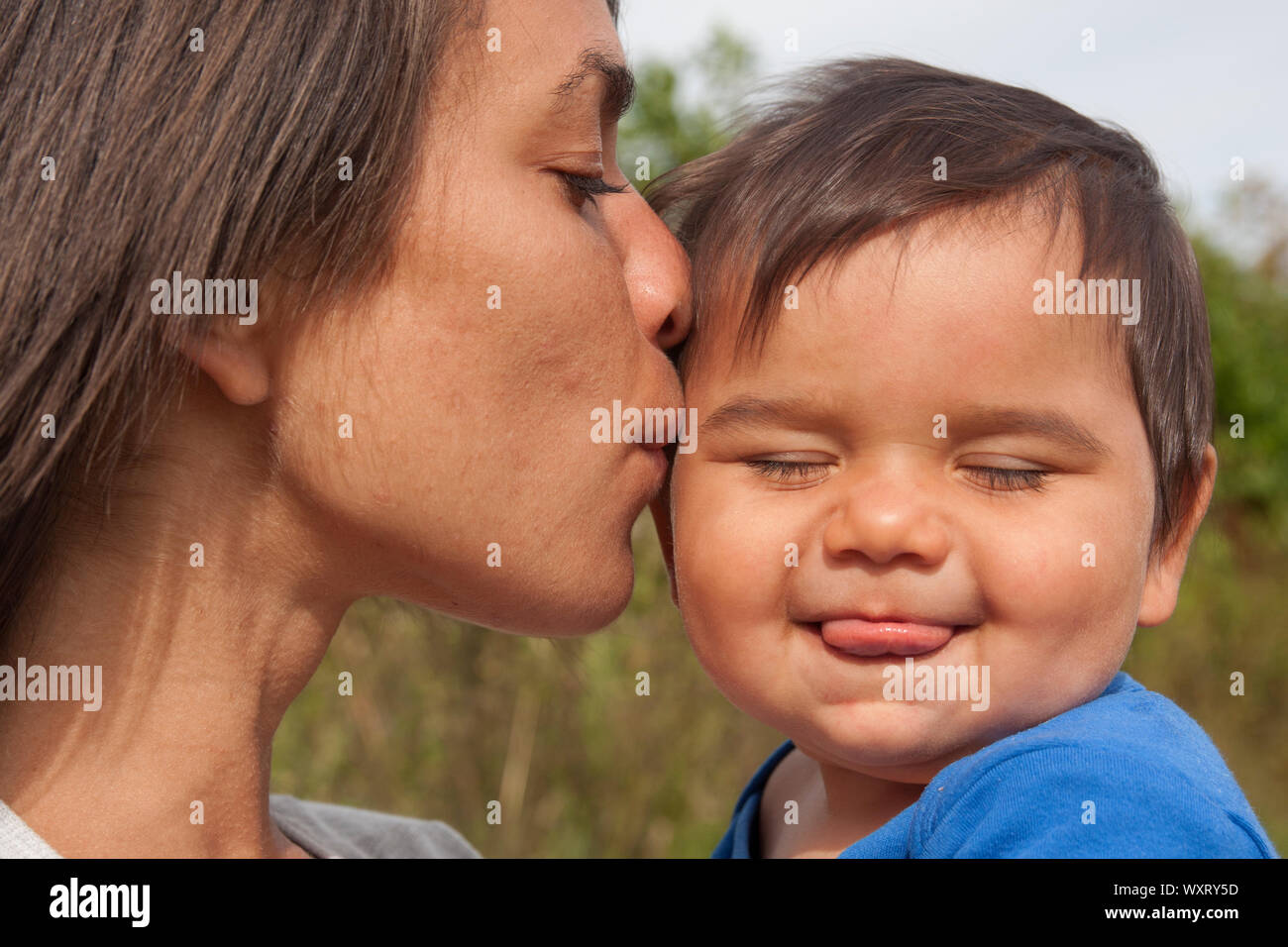 Madre Bebé besos en la mejilla Foto de stock