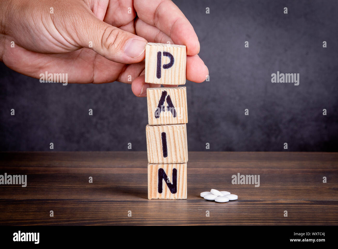 Concepto de dolor. Letras de madera y pastillas de color blanco Foto de stock