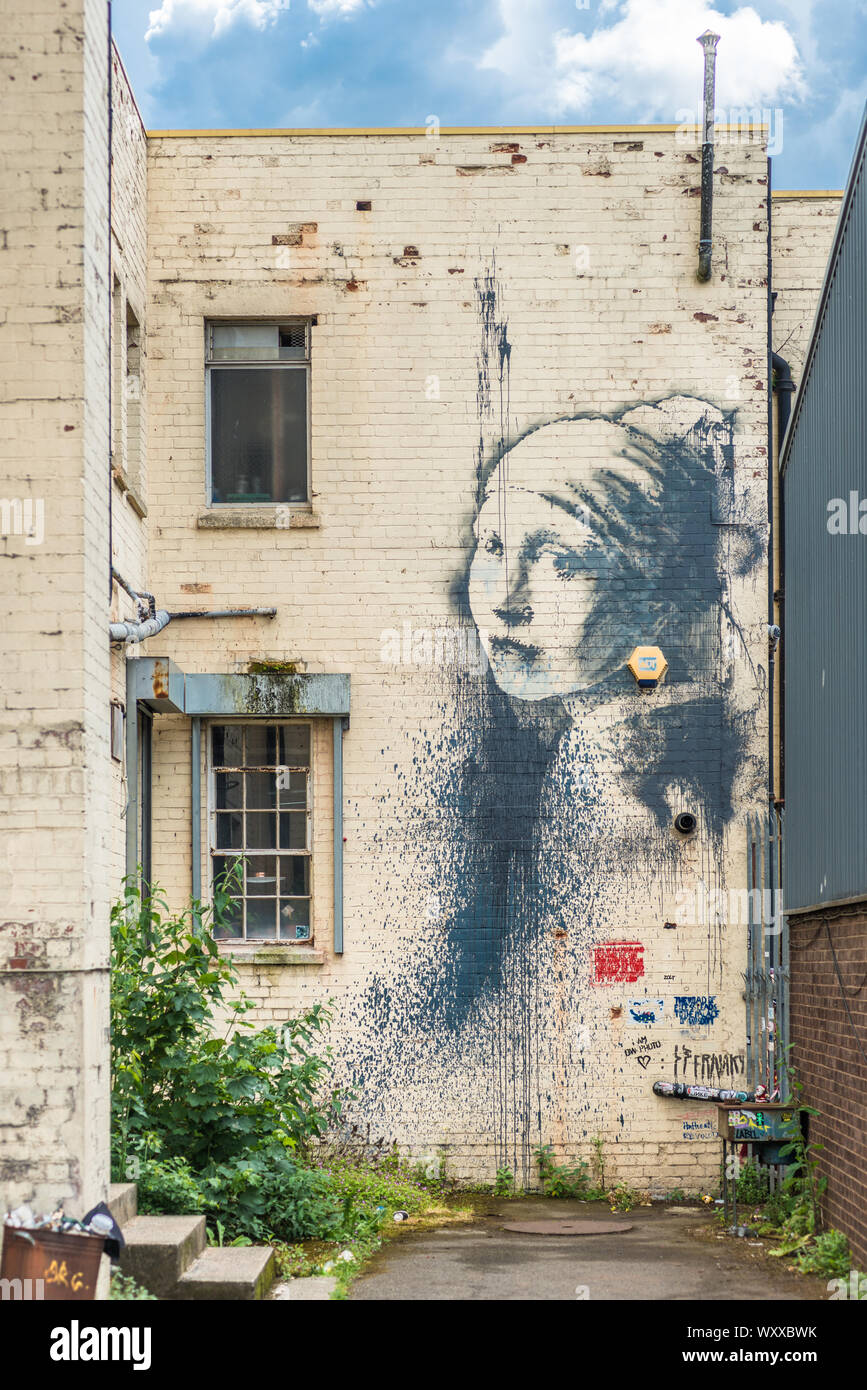 Chica con un tímpano perforado - una obra basada alrededor de una alarma  por el artista Banksy en la pared de un callejón en el Albion Docks,  Bristol, Inglaterra, Reino Unido Fotografía