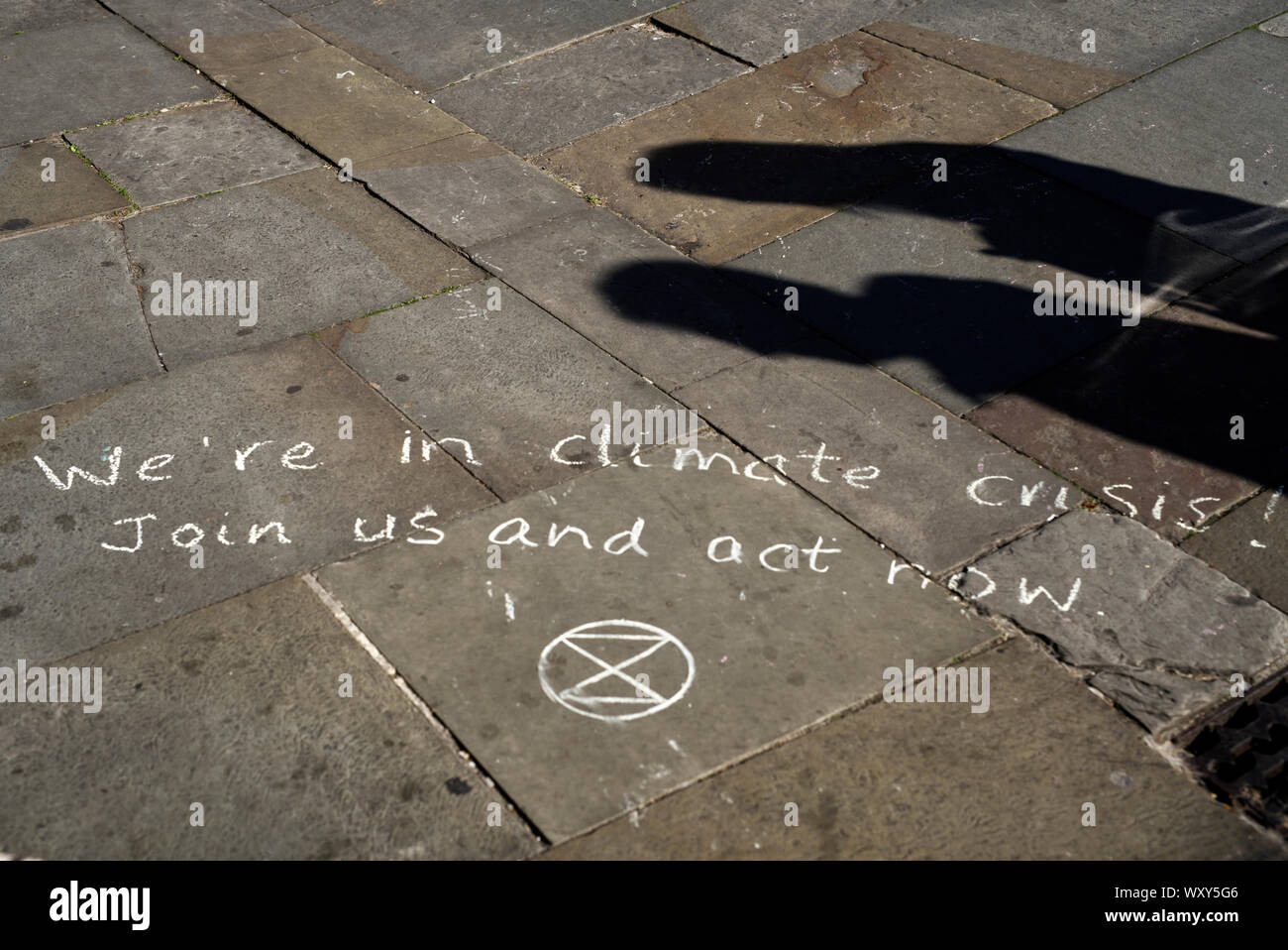 Dos personas leyendo un mensaje escrito sobre pavimento al público para crear conciencia sobre el cambio climático. Mensaje fue escrito por extinción rebelión Foto de stock