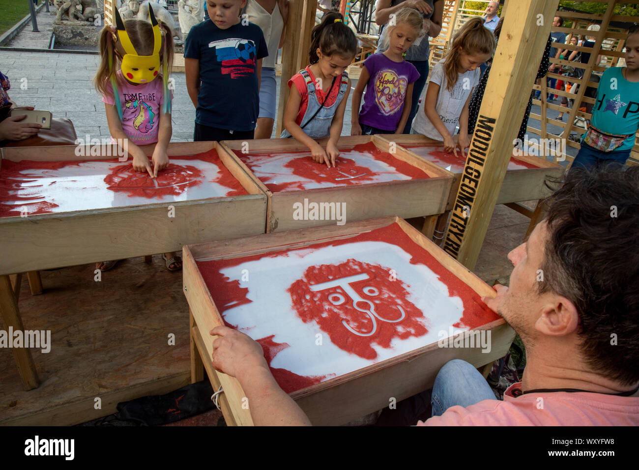 Un artista que enseña a los niños el arte de pintar con arena sobre una mesa especial en Moscú Muzeon Park durante un festival de la ciudad, Rusia Foto de stock