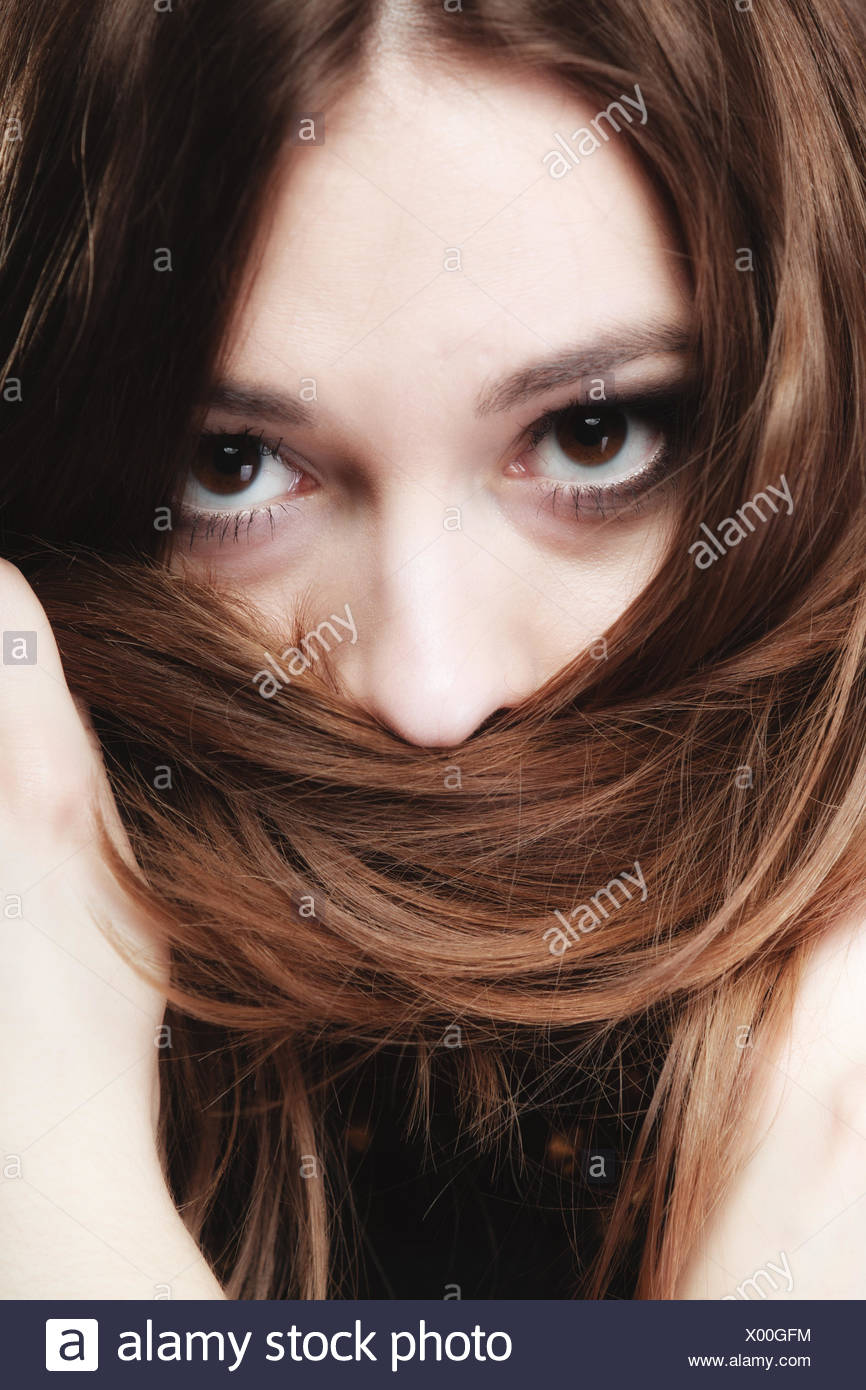 Mujer cubre el rostro por largos pelos marrones Foto de stock