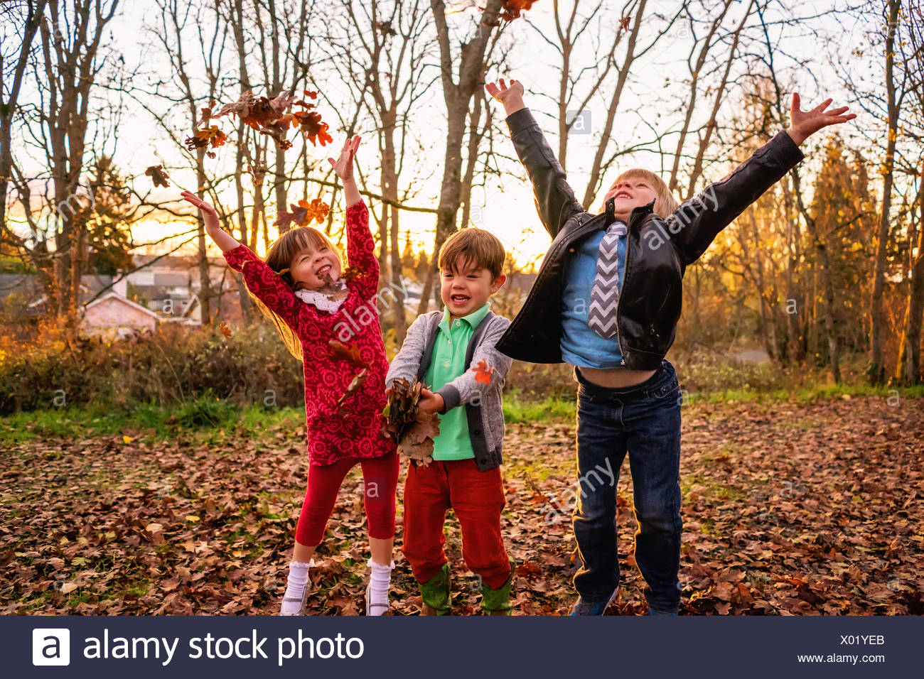 Dos niños y una niña arrojando deja en el aire Foto de stock