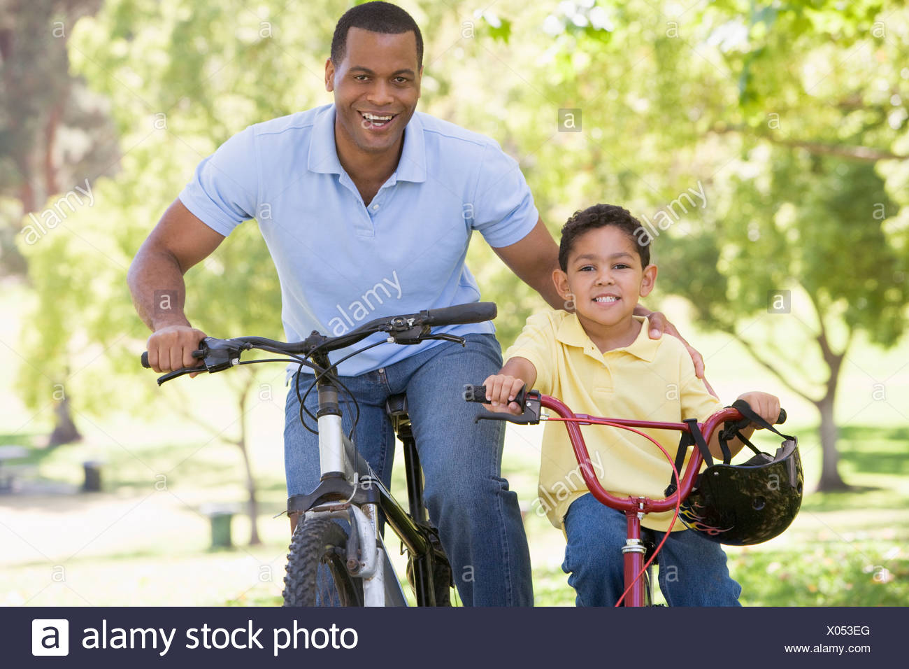 Hombre y muchacho sobre bicicletas afuera sonriendo Foto de stock