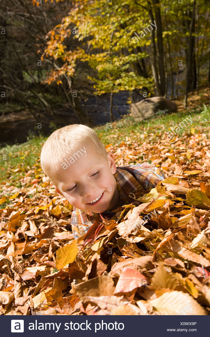 Niño jugando en hojas de otoño Foto de stock