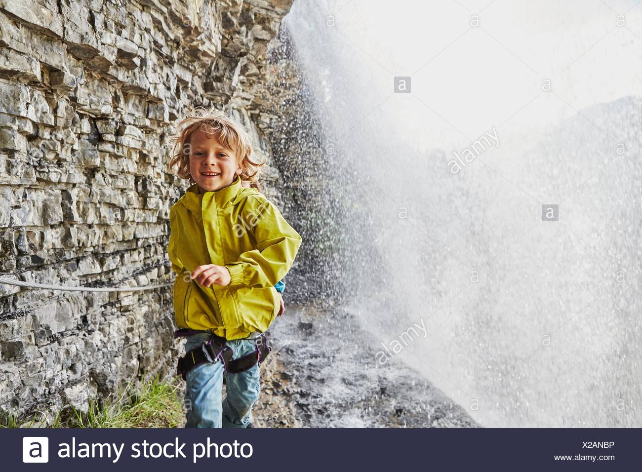 Muchacho caminando debajo de la cascada, sonriendo Foto de stock