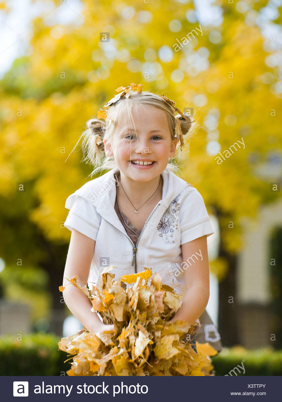 Niña jugando en hojas caídas. Foto de stock