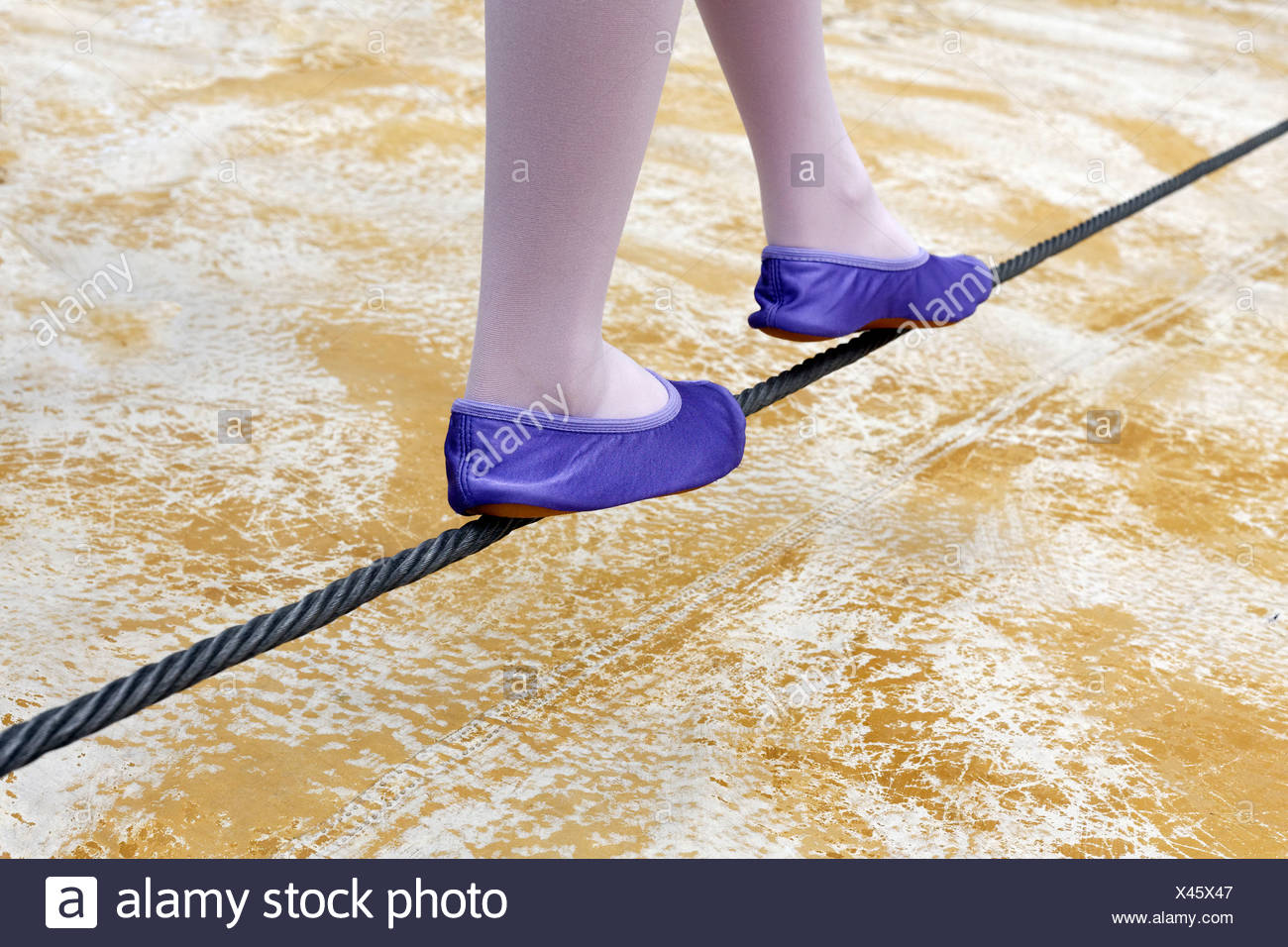 Niña zapatos de ballet en equilibrio sobre un cable de acero, justo por encima del suelo Foto de stock