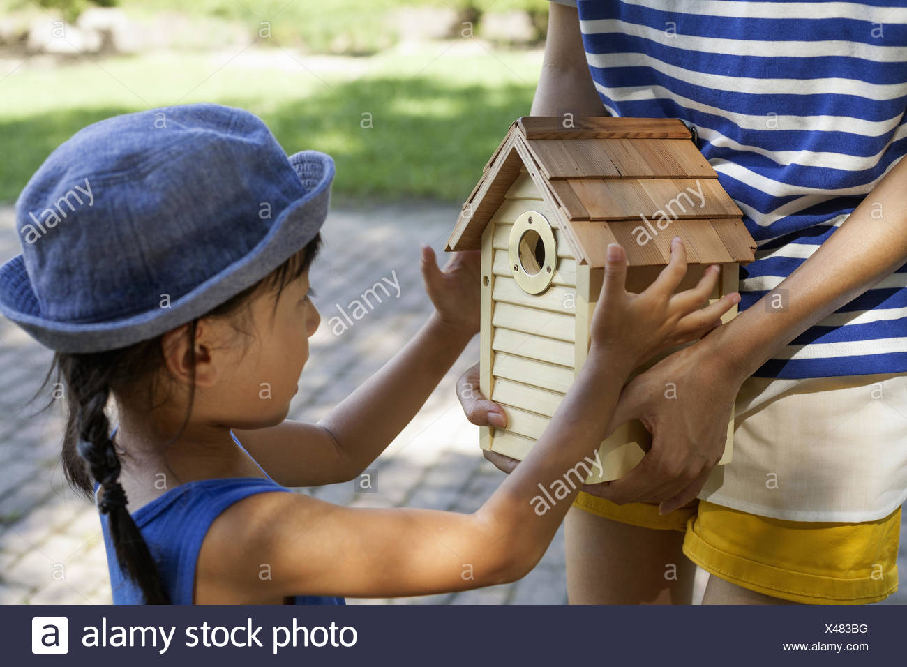 Joven llevando un vestido y sombrero para el sol, sosteniendo una casa de aves. Foto de stock