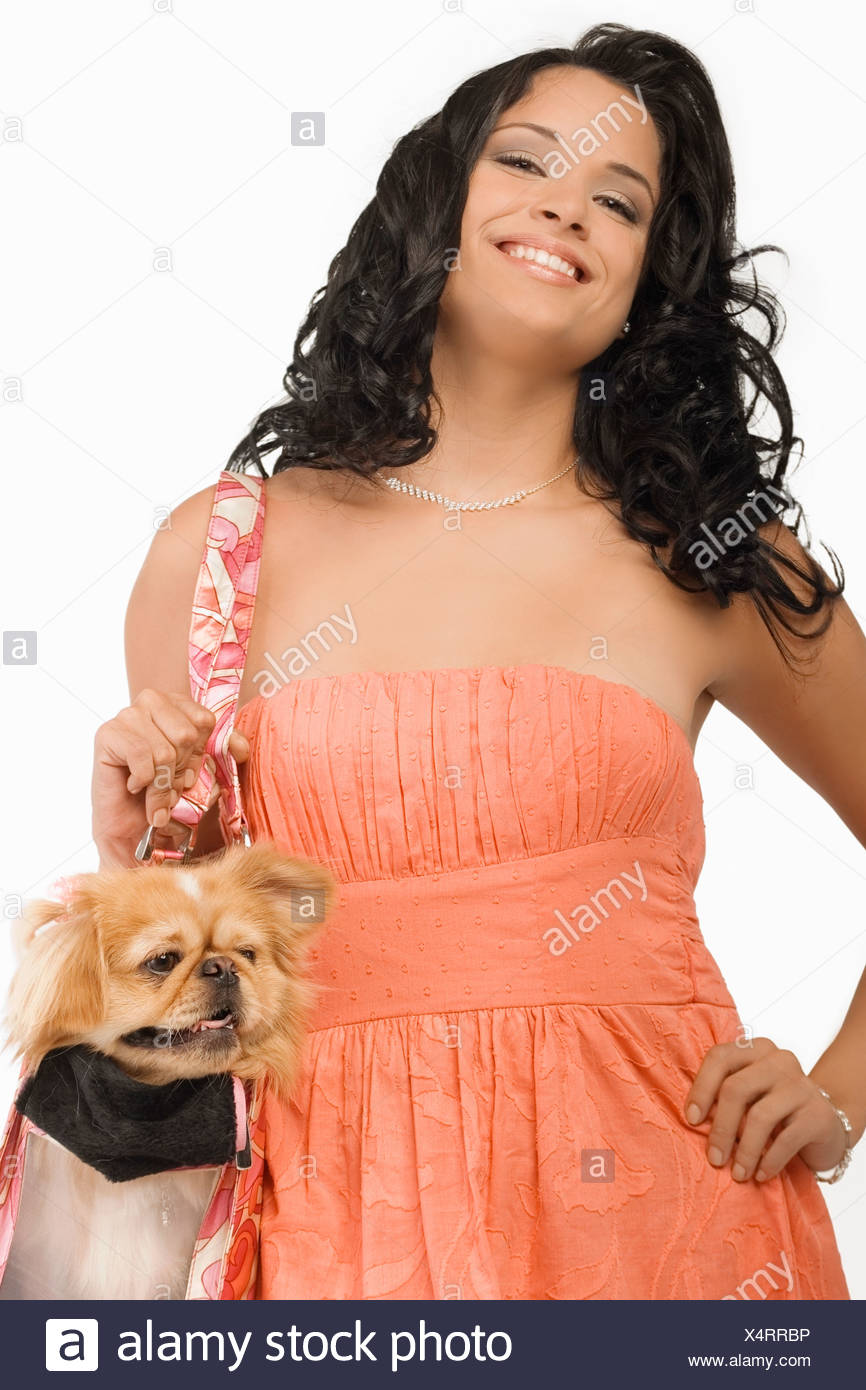 Retrato de una joven mujer que llevaba un perro Pomerania en una bolsa y sonriente Foto de stock