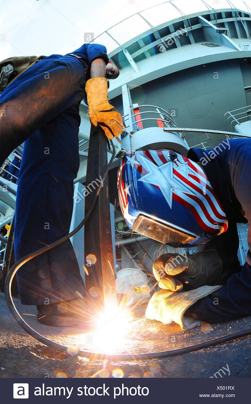 Océano Pacífico Septiembre 14, 2010 técnico de mantenimiento Casco Bombero Josh Hazelett soldaduras un bracketing de hierro para la cubierta mientras Hull Foto de stock