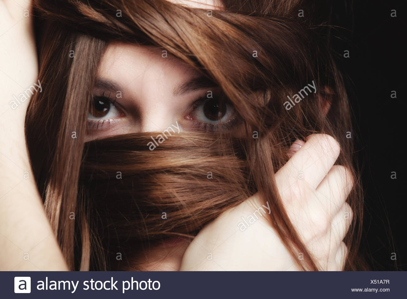 Mujer cubre el rostro por largos pelos marrones Foto de stock