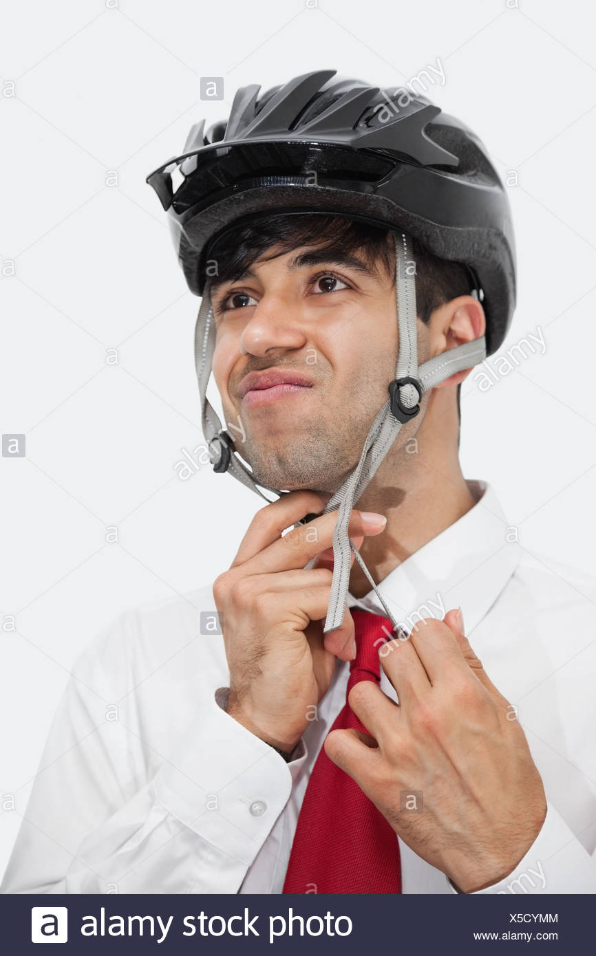Empresario Indio Ajuste De Casco De Bicicleta Mientras Miraba Lejos Contra El Fondo Gris Fotografia De Stock Alamy