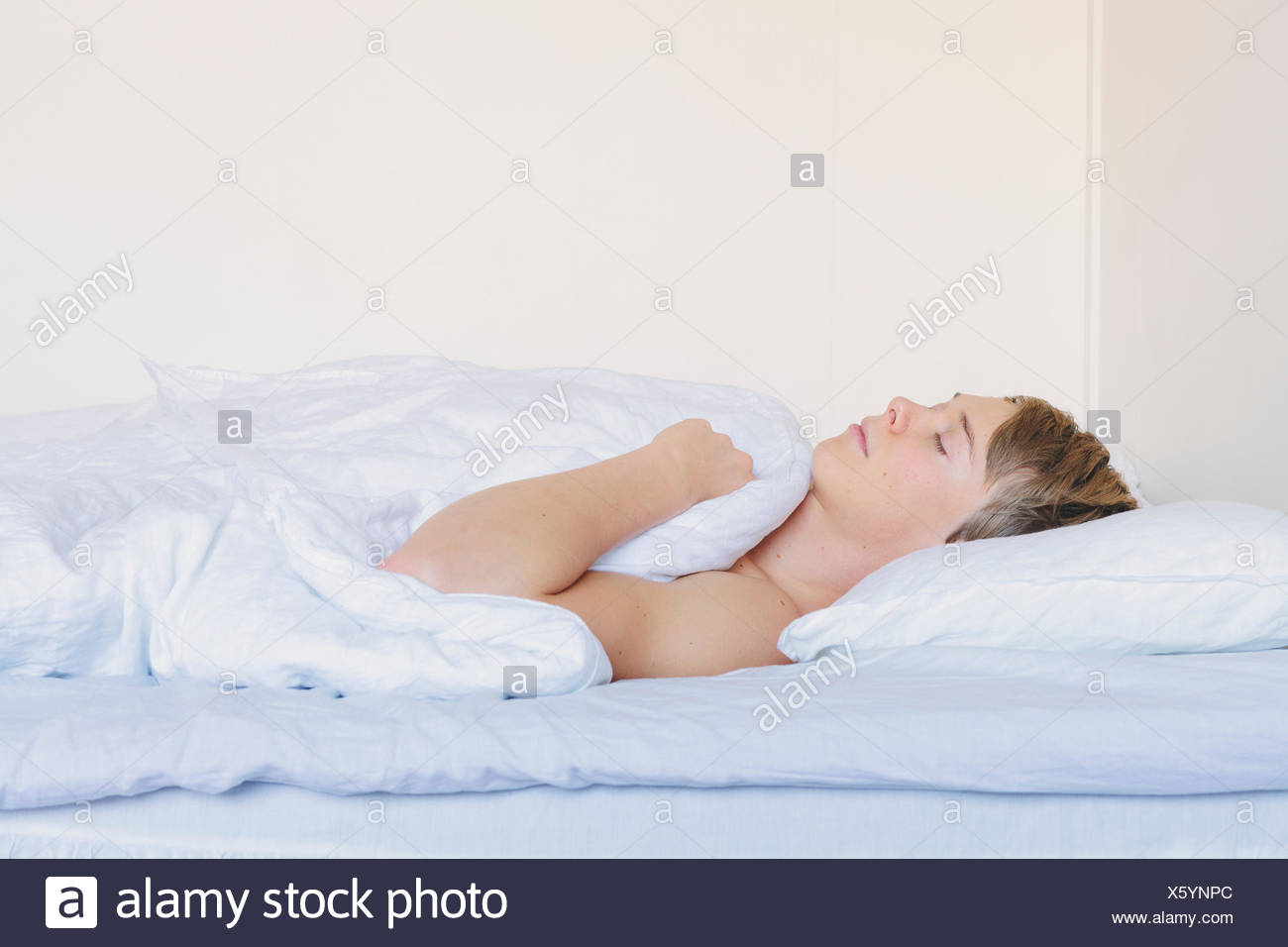 Finlandia, Helsinki, Retrato de joven durmiendo en cama bajo Finlandia, Helsinki, retrato del bostezo joven envuelto en