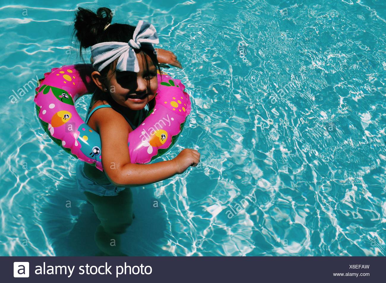 Un alto ángulo de vista de niña alegre nadar en piscina con salvavidas Foto de stock