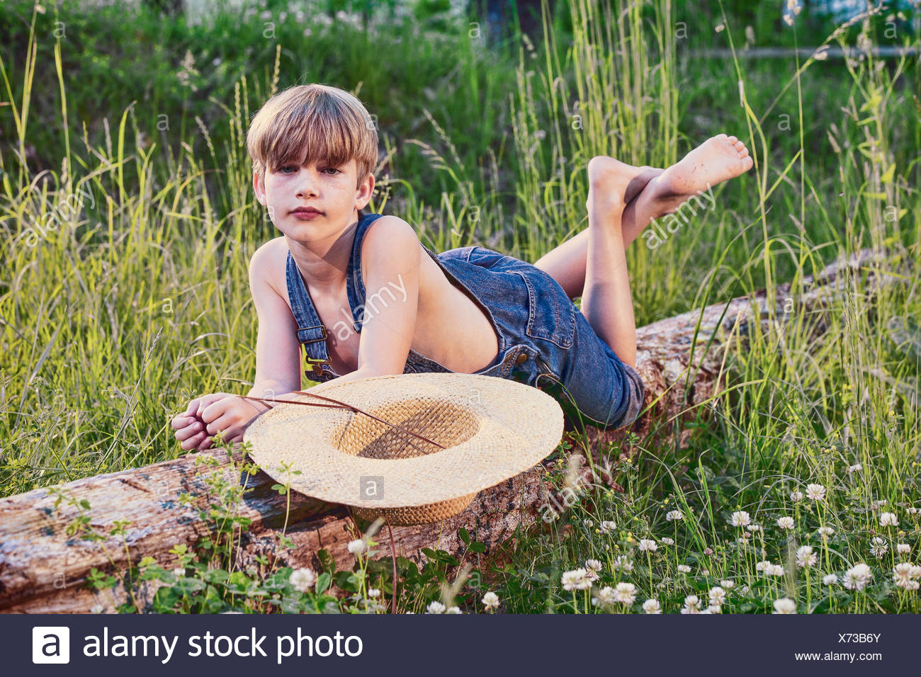 Joven vistiendo un mono azul poniendo en árbol caído Foto de stock