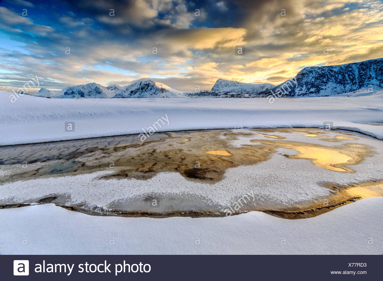 El amanecer dorado se refleja en una piscina de aguas cristalinas donde la nieve es casi derretido. Las Islas Lofoten Noruega Europa Haukland Foto de stock