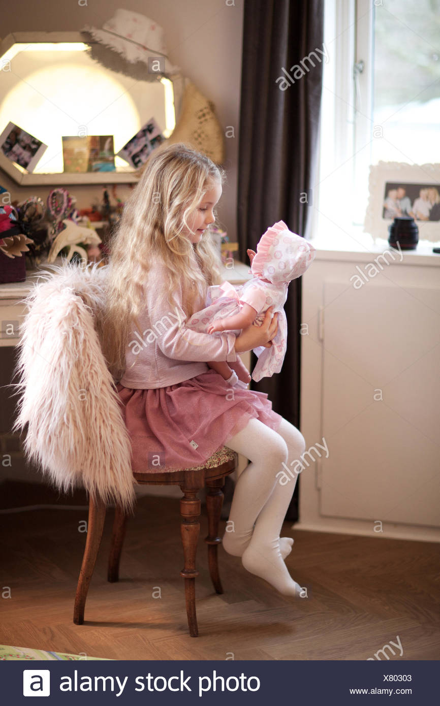 Niña jugando con su muñeca. La guardería, cabrito, sala de juegos, juego de aparentar. Foto de stock
