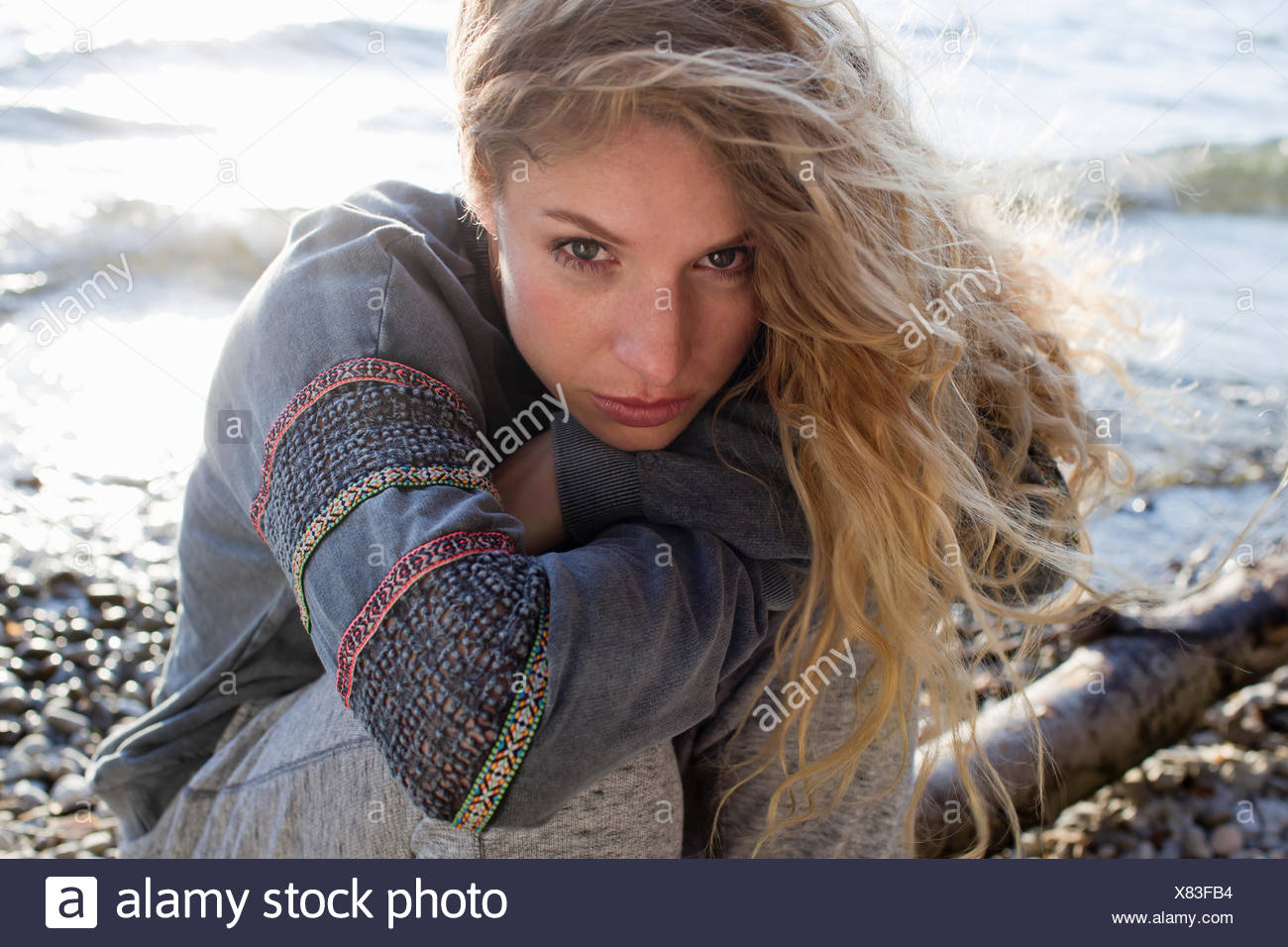 Mujer sentada en la playa ventosa Foto de stock