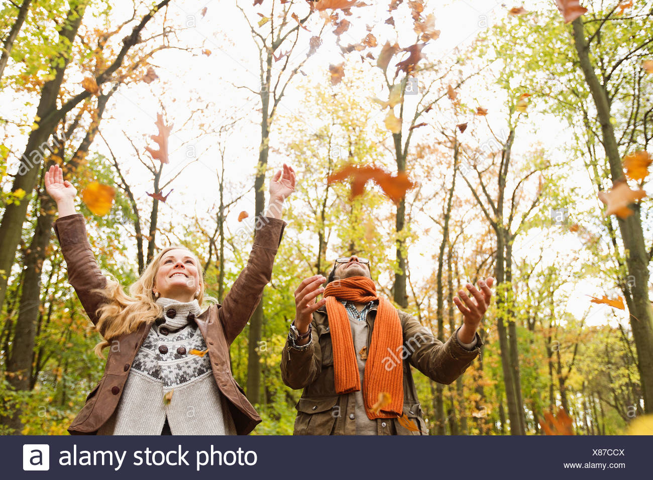 Pareja sonriente jugando en hojas de otoño Foto de stock