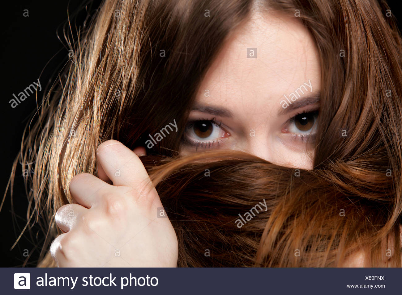 Closeup mujer cubre el rostro por largos pelos marrones Foto de stock