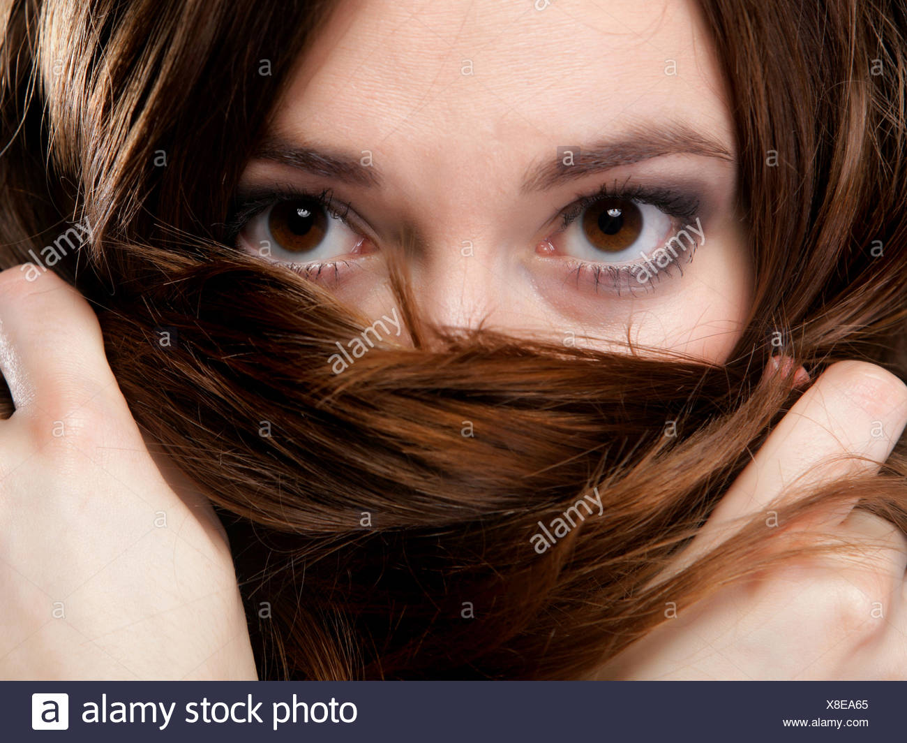 Closeup mujer cubre el rostro por largos pelos marrones Foto de stock