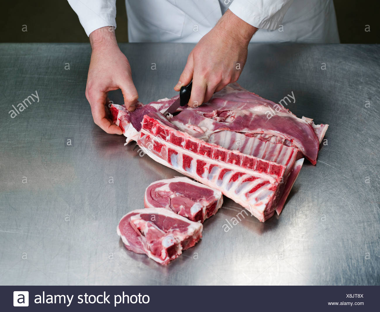 Un carnicero cortando una carne Foto de stock