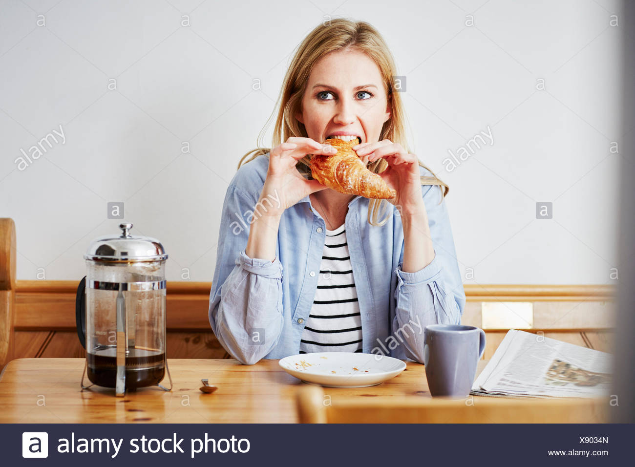 Mujer adulta media comiendo croissant Foto de stock