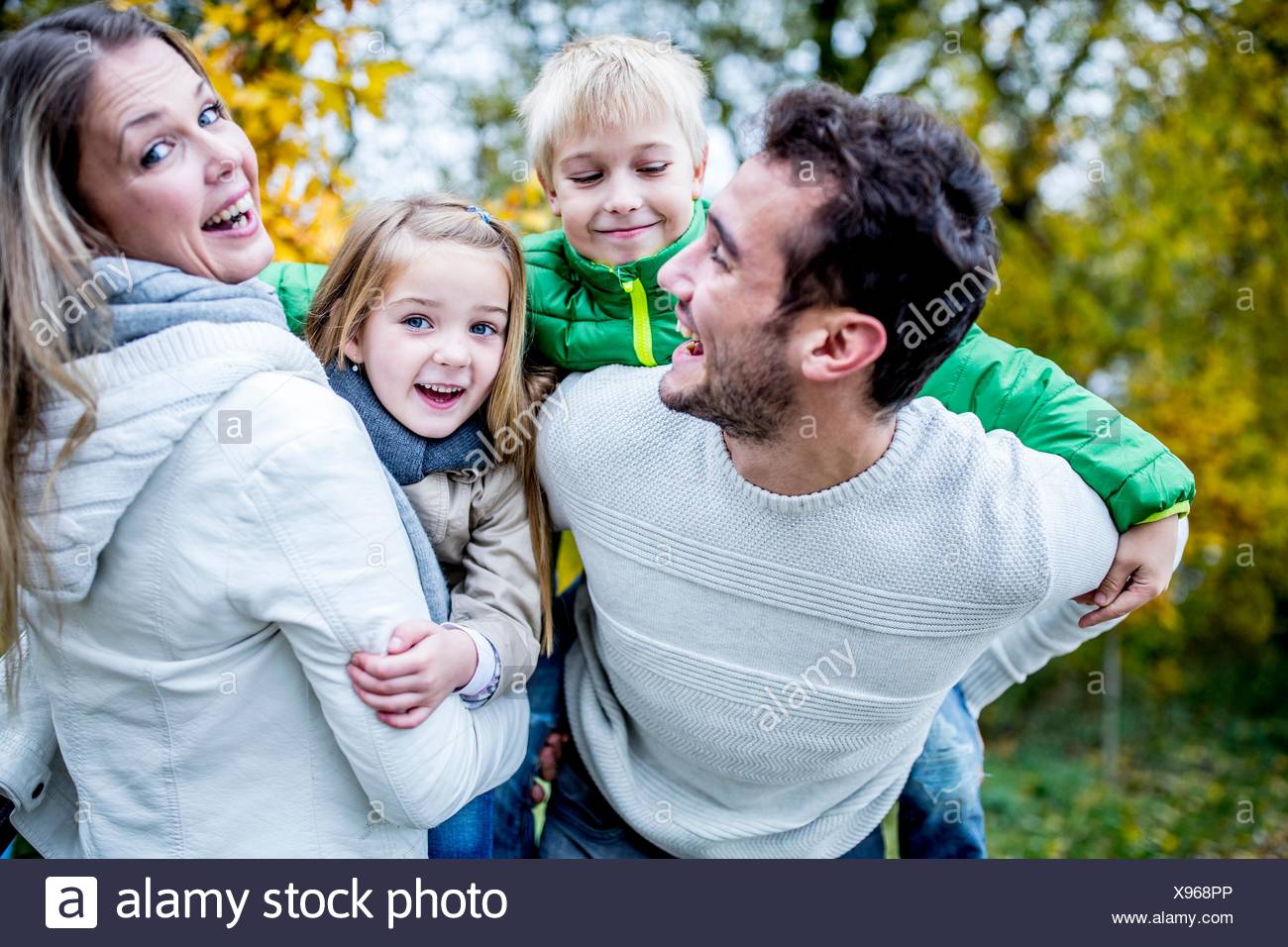 Modelo liberado. Los padres llevan a sus hijos en otoño, riendo. Foto de stock