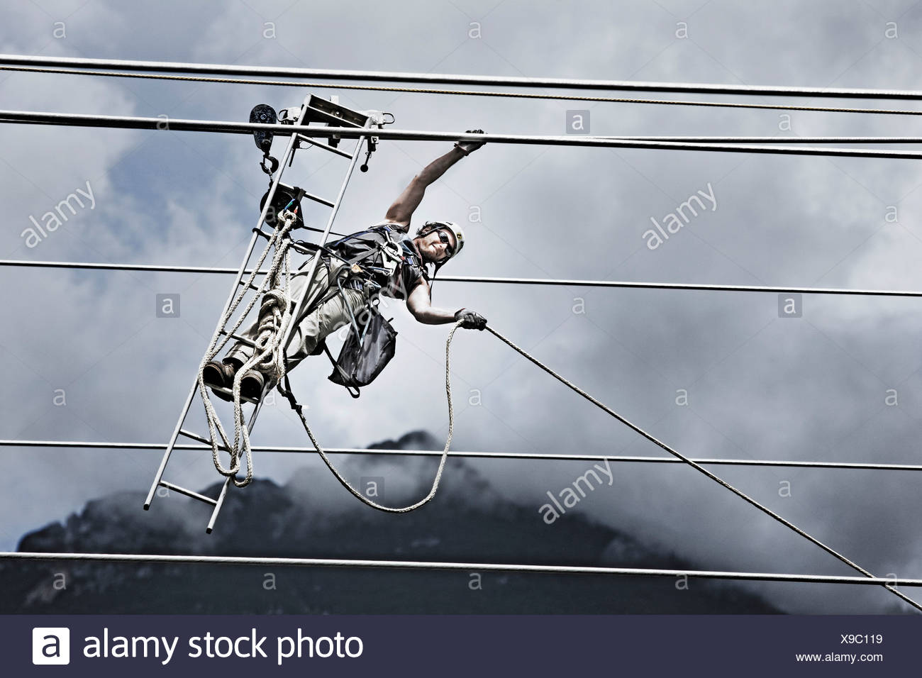 Servicio técnico de alta tensión tirando de una cuerda para llegar a la próxima torre Foto de stock
