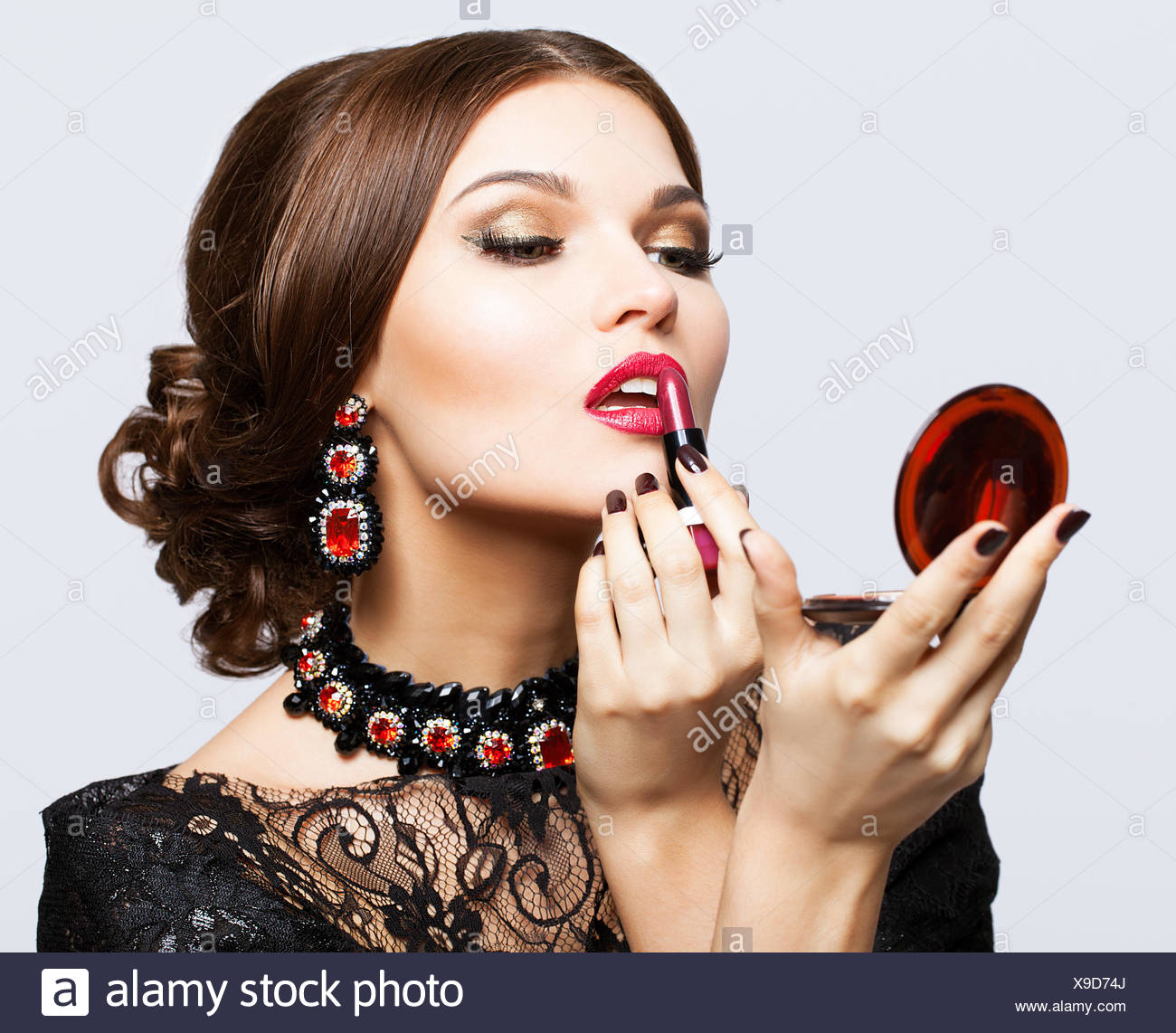 Maquillaje De Morena Hermosa Joven Mujer De Vestido Negro Con Lapiz Labial Y Espejo En Manos Fotografia De Stock Alamy