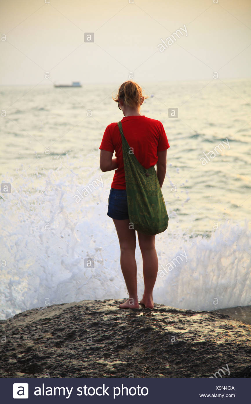 Las olas rompen en frente de mujer en la playa; Koh Tao, Tailandia Foto de stock