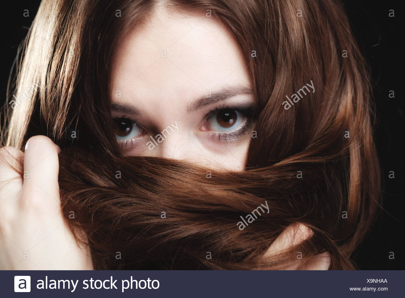 Mujer cubre el rostro por largos pelos marrones Foto de stock