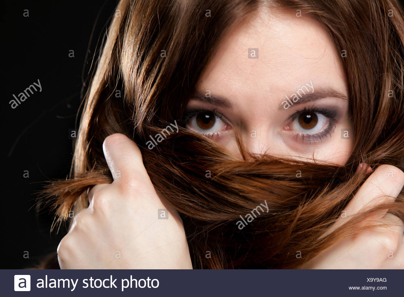 Closeup mujer cubre el rostro por largos pelos marrones Foto de stock