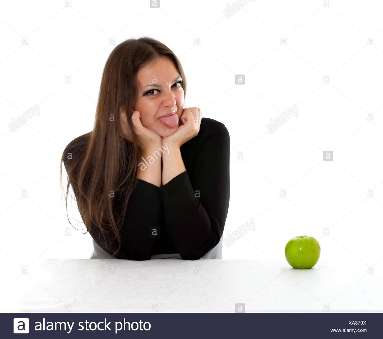 Chica con manzana verde mostrando la lengua Foto de stock