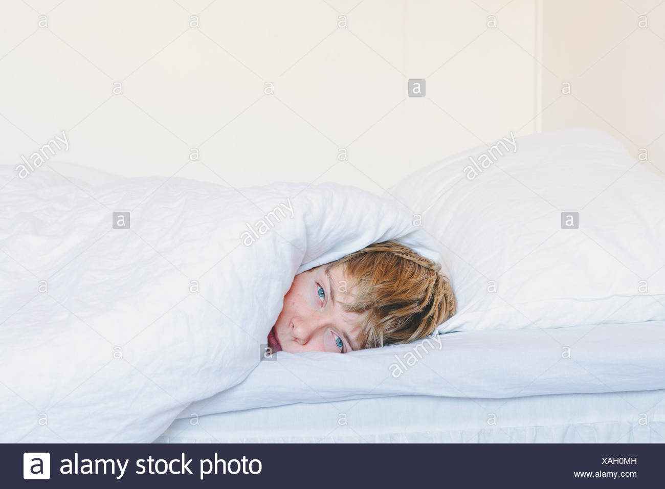 Finlandia, Helsinki, retrato del joven tumbado en la cama Finlandia, Helsinki, retrato del bostezo joven envuelto en